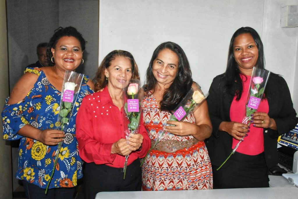 Servidoras sendo agraciadas com rosas e uma mensagem de felicitações em referência ao dia das mulheres