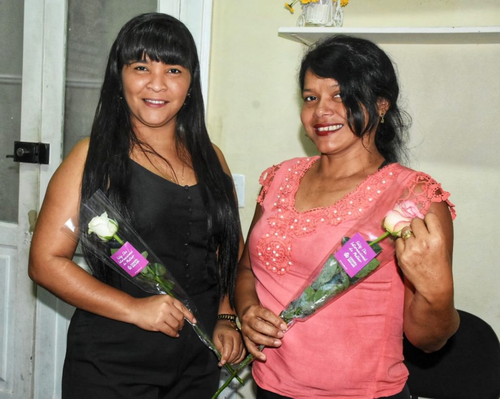 Servidoras sendo agraciadas com rosas e uma mensagem de felicitações em referência ao dia das mulheres